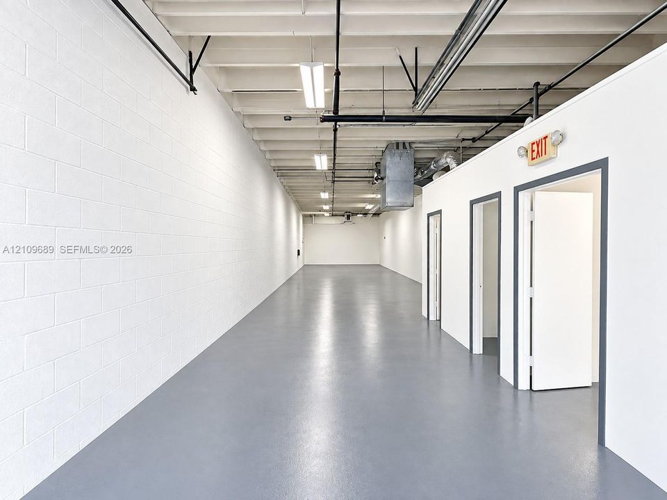 Industrial interior featuring freshly  painted walls and floors, exposed ceiling. and recessed lighting