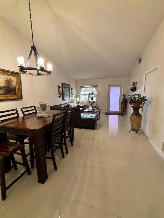 Vaulted ceilings, large-format tile flooring, arched window, and a rustic iron chandelier