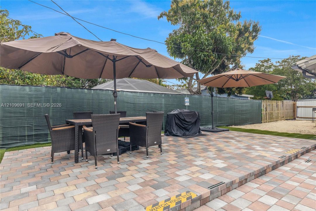 Outdoor patio featuring multi-tonal concrete pavers, tiered levels, and a privacy screen perimeter