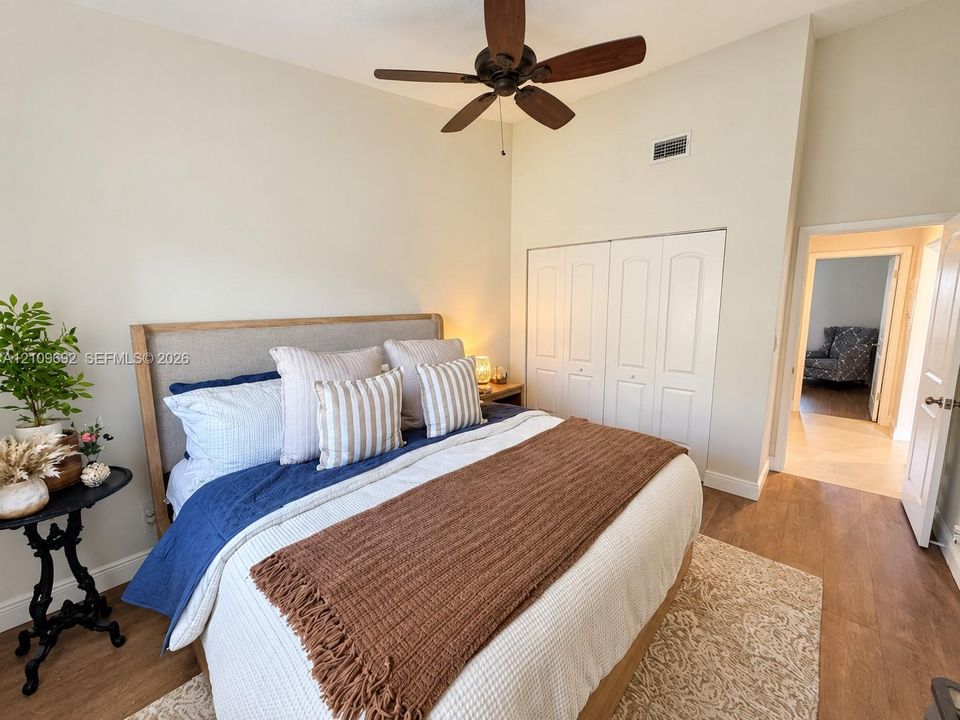 Room featuring wood-finish flooring, vaulted ceilings, a ceiling fan, and built-in closet cabinetry