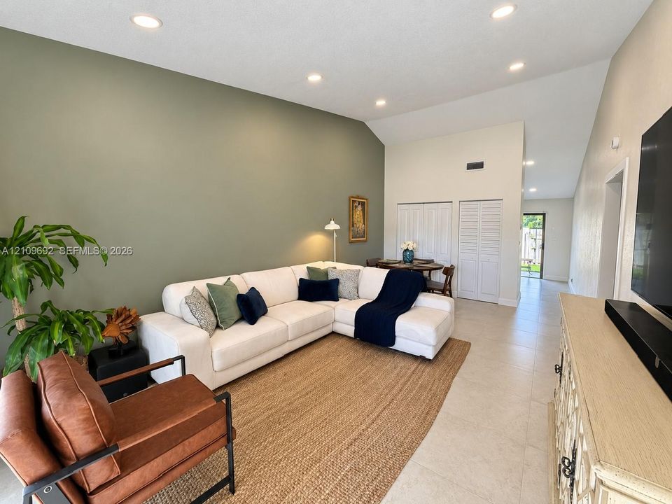 Vaulted ceilings featuring recessed lighting, ceramic tile flooring, and a decorative accent wall