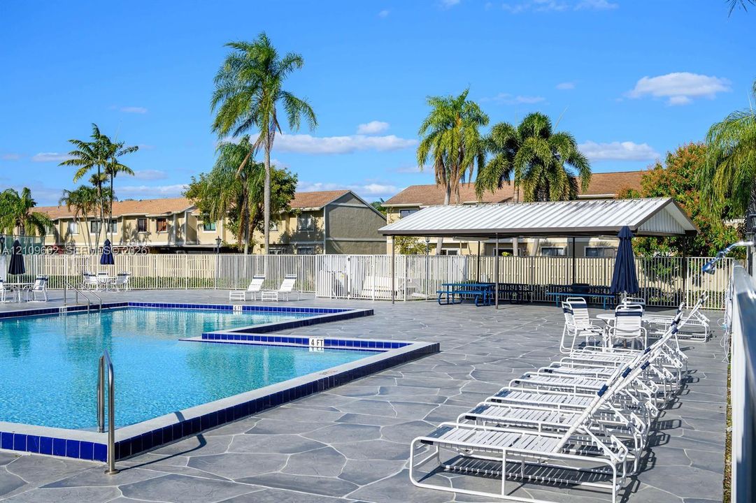 Swimming pool with tiled perimeter, stone-finish deck, and covered pavilion structure