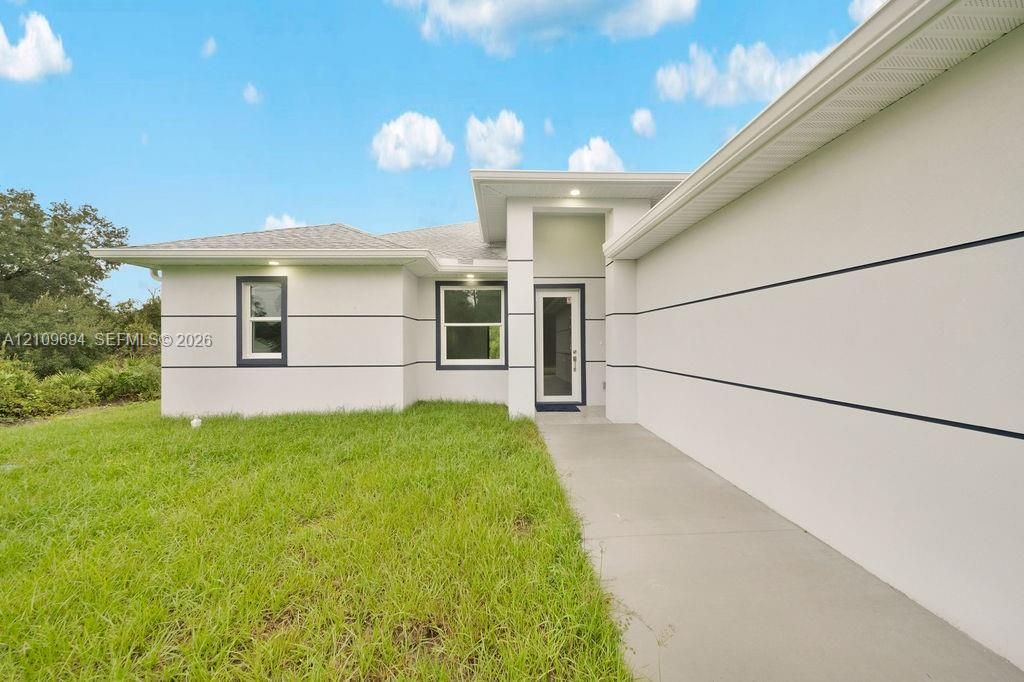 Modern exterior featuring stucco finish with horizontal trim detailing, a recessed covered entryway, and a concrete walkway