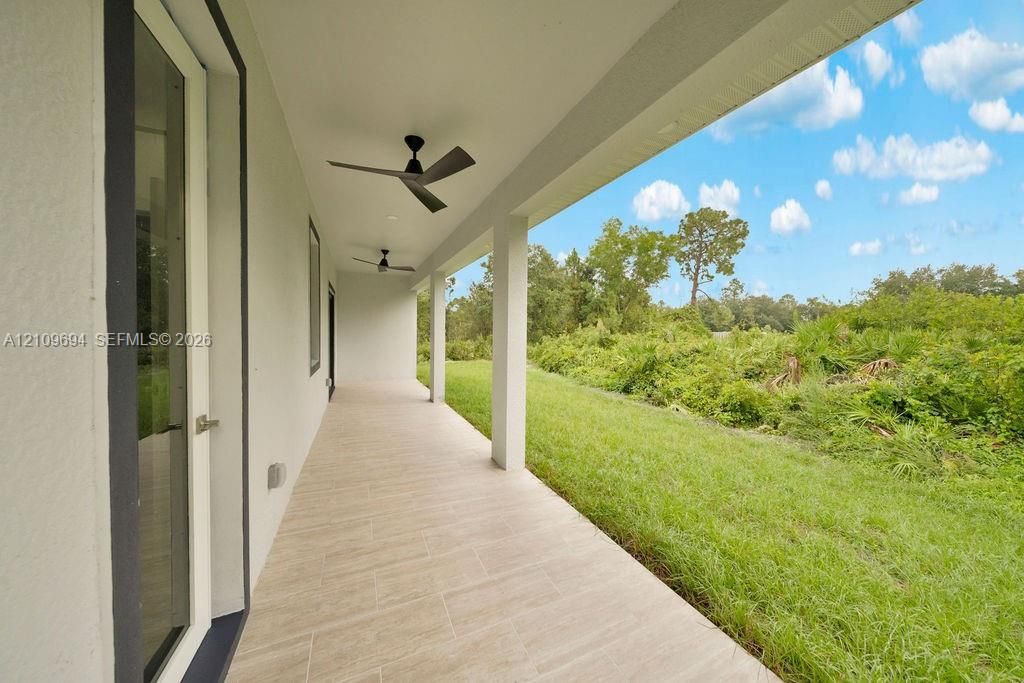 Covered lanai featuring tile flooring, structural columns, and mounted ceiling fans