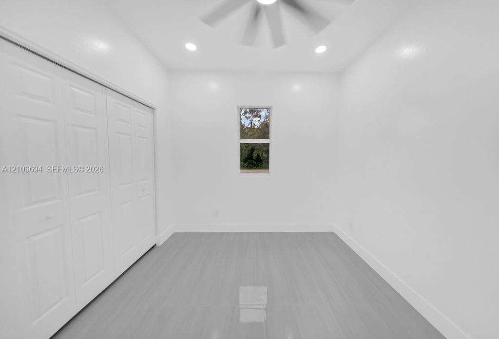 Neutral-toned interior featuring wood-finish flooring, recessed lighting, a ceiling fan, and built-in closet cabinetry