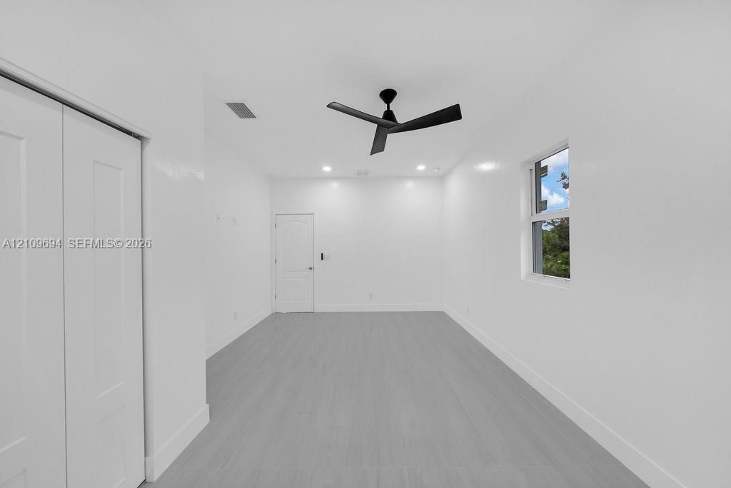 Interior room featuring neutral wall finishes, wood-finish flooring, a matte black ceiling fan, recessed lighting, and a single-panel interior door