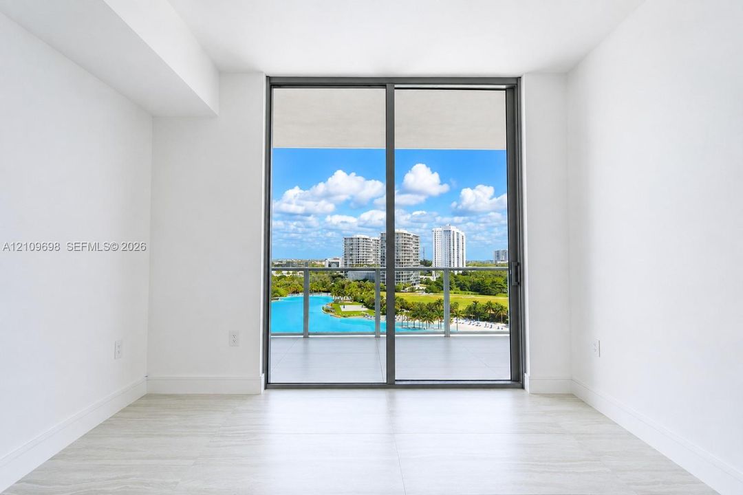 Floor-to-ceiling sliding glass door providing access to a covered balcony with a glass railing