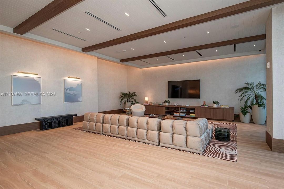 Recessed lighting, wood-finish ceiling beams, wood-finish flooring, built-in media console, and wall-mounted art lighting