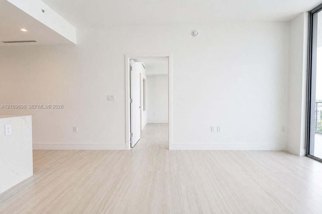 Interior space featuring wood-finish flooring, floor-to-ceiling glass panel door, and white solid-surface peninsula countertop