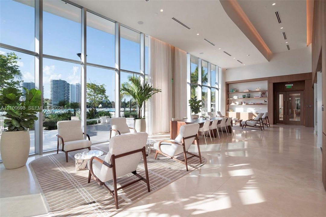Floor-to-ceiling windows, high ceilings with recessed lighting, stone flooring, and built-in wood shelving