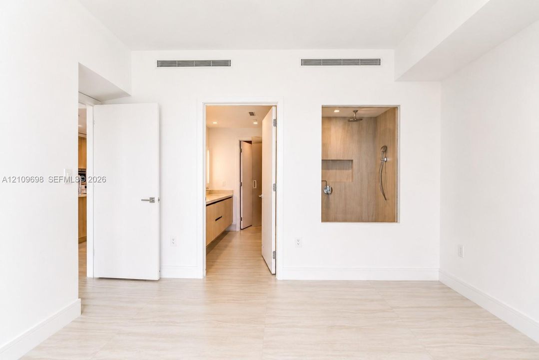 Interior space featuring wood-finish flooring, a recessed shower enclosure with wood-finish wall tile, a built-in recessed shower niche, and a wall-mounted shower fixture
