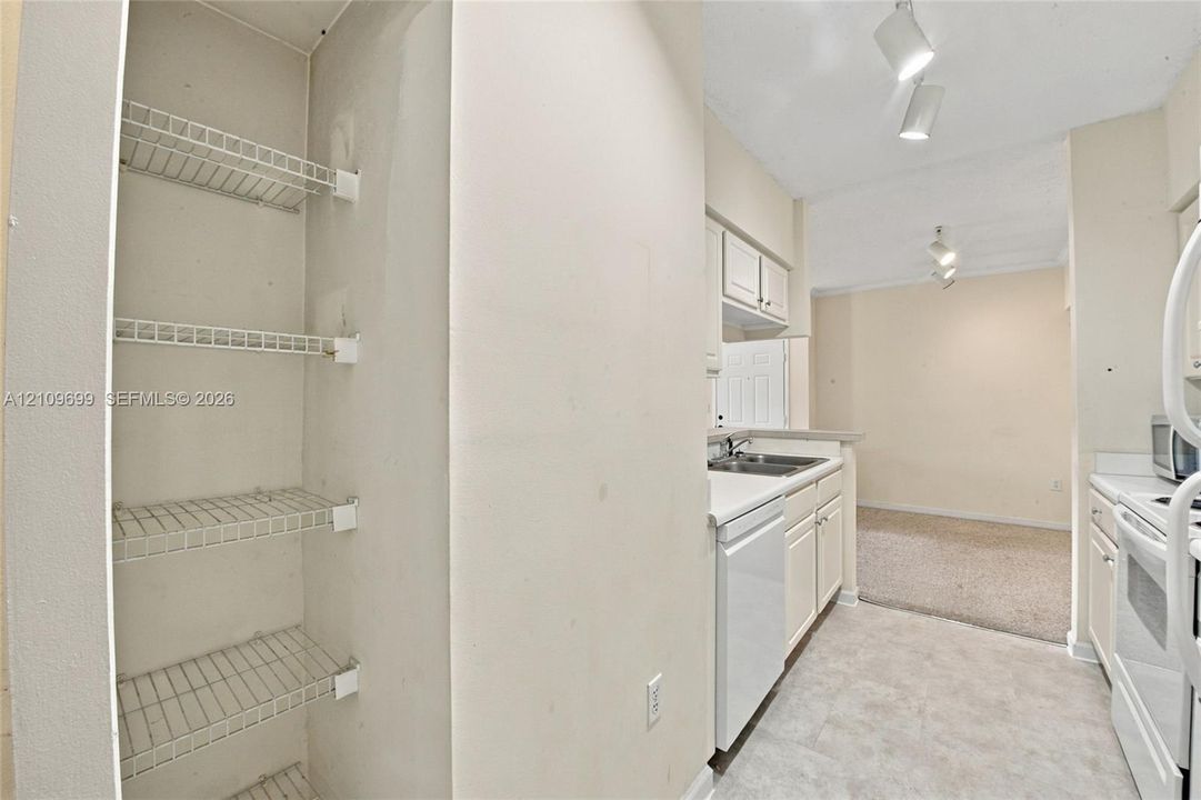 Kitchen featuring white cabinetry, wire shelving, tile flooring, and integrated track lighting