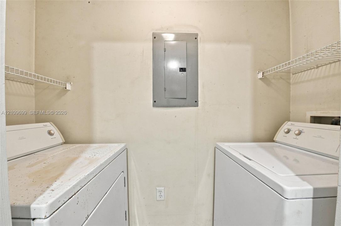 Utility space featuring wall-mounted wire shelving and a centrally located electrical panel