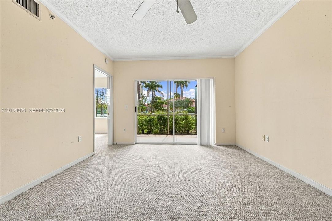 Living space featuring textured ceiling, neutral wall finish, wall-to-wall carpeting, ceiling fan, and sliding glass doors