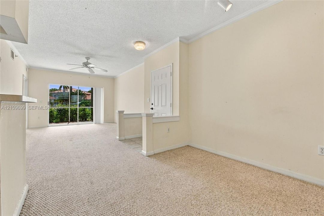 Interior space featuring carpeted flooring, a ceiling fan, crown molding, and sliding glass doors providing outdoor access