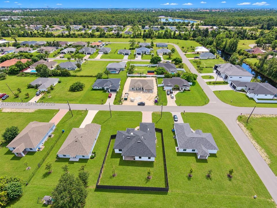 Aerial perspective of a suburban neighborhood featuring paved streets, established lot lines, and expansive green spaces