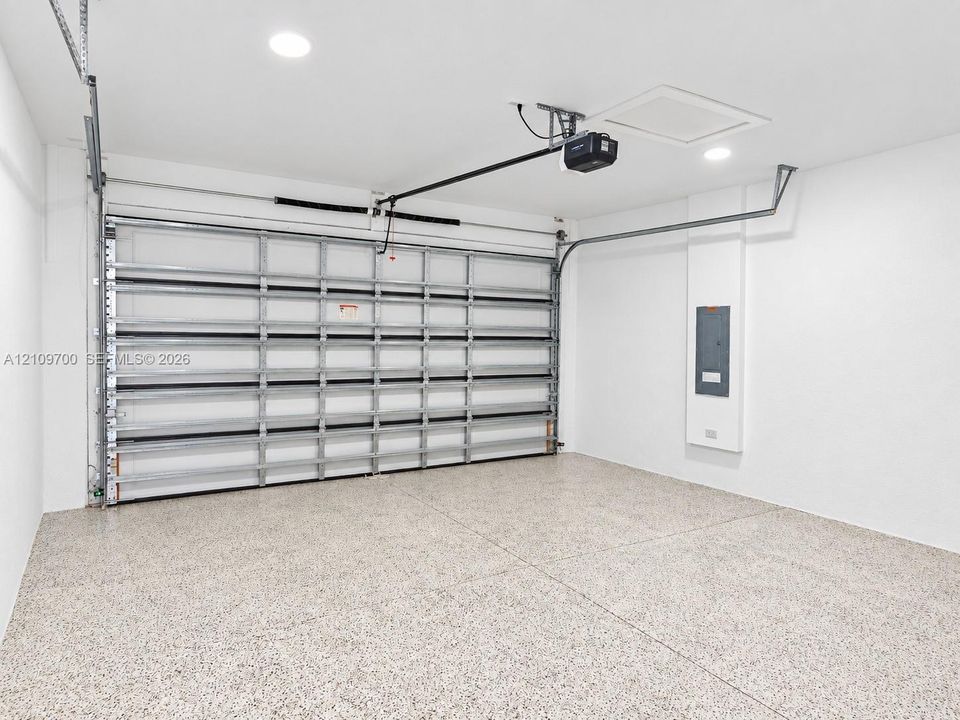 Finished garage space featuring epoxy flooring, recessed lighting, and a metal roll-up door