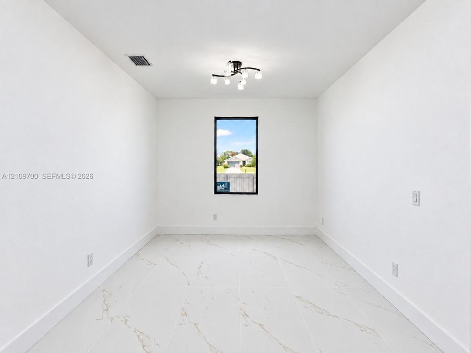 Interior room featuring large-format tile flooring with veining, a modern multi-light fixture, and a vertical window with a dark frame