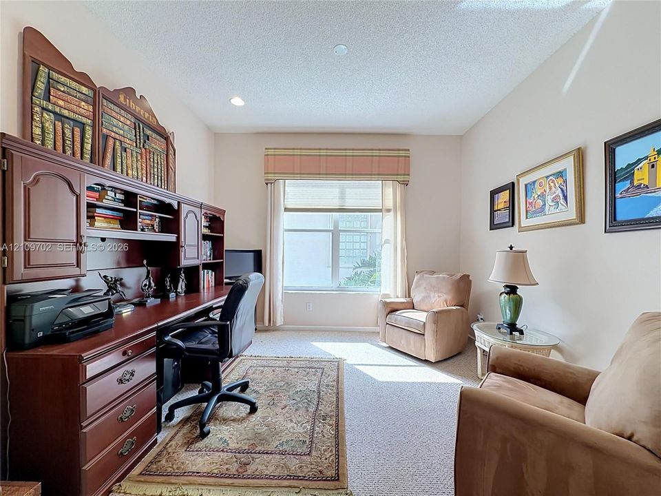 wood cabinetry with integrated shelving and desk surface, carpeted flooring, and large window with cornice board