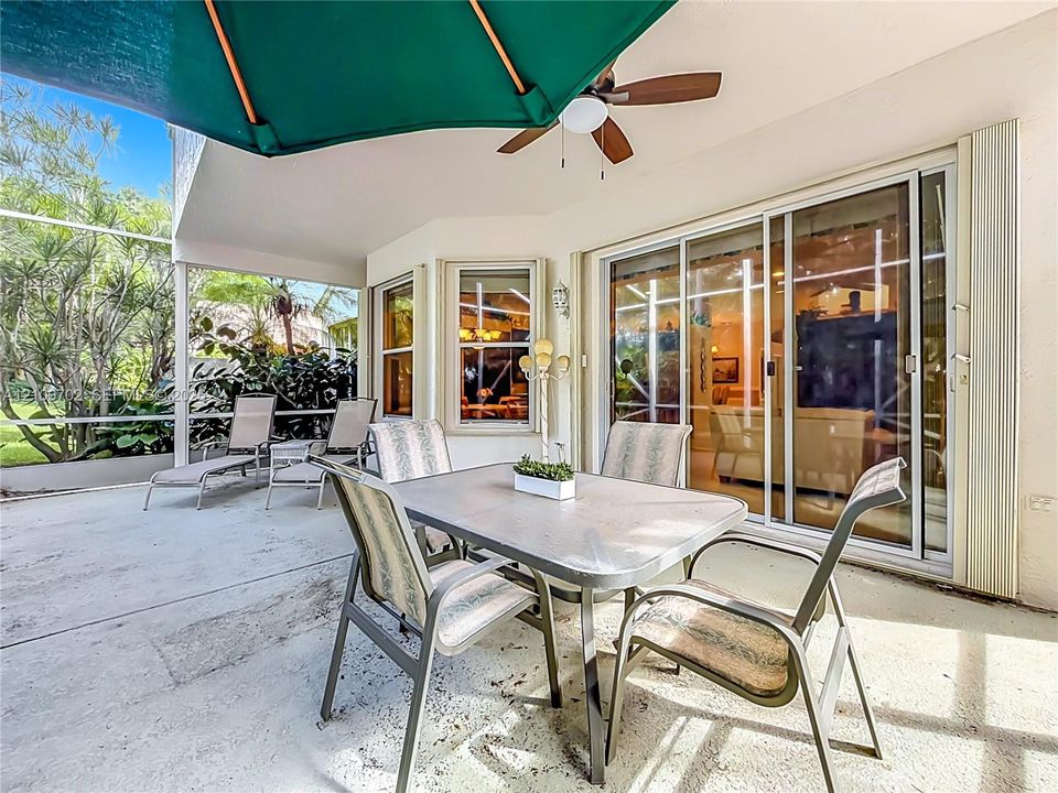 Screened-in covered lanai featuring a concrete floor, built-in ceiling fan, and multi-panel sliding glass doors