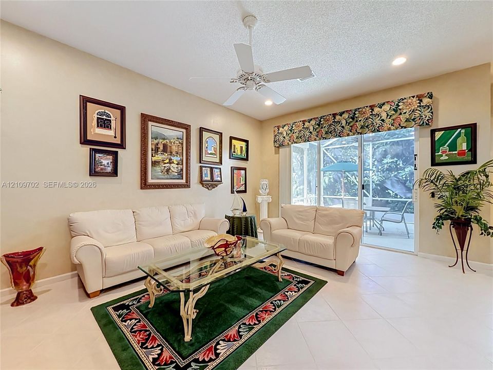 Light-toned tile flooring, white ceiling fan, and sliding glass doors leading to a screened enclosure