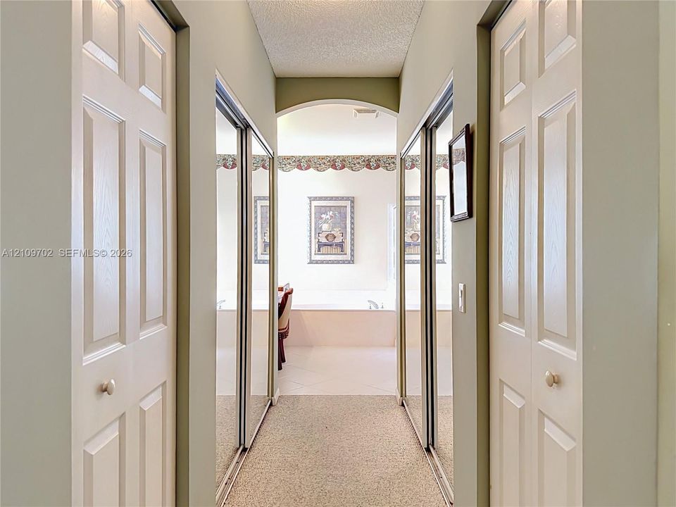 Hallway featuring six-panel doors, dual mirrored sliding closet doors, and an arched entry