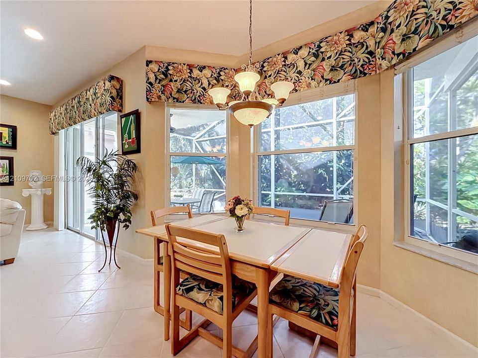 Sun-filled breakfast nook featuring large bay windows, recessed lighting, a multi-arm chandelier, light-toned tile flooring, and sliding glass doors