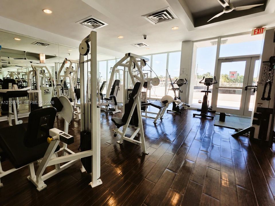 Fitness center featuring floor-to-ceiling windows, wood-finish flooring, recessed lighting, and mirrored walls