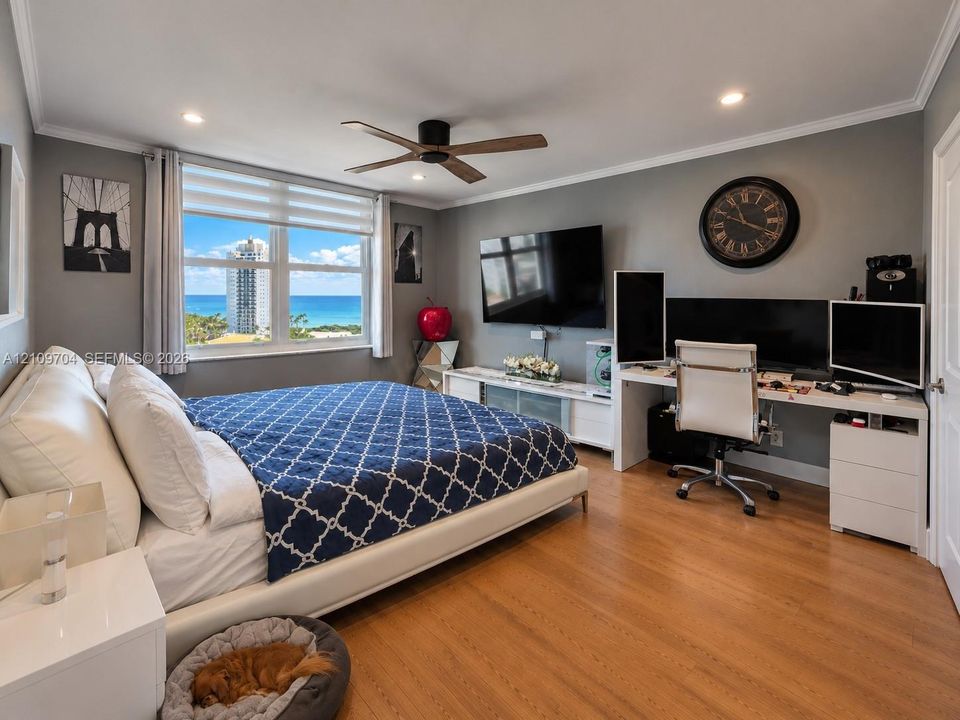 Room featuring wood-finish flooring, recessed lighting, a modern ceiling fan, and large windows with ocean and coastal scenery
