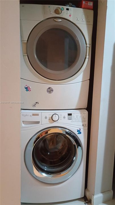 Stacked front-loading washer and dryer unit housed in a recessed laundry alcove