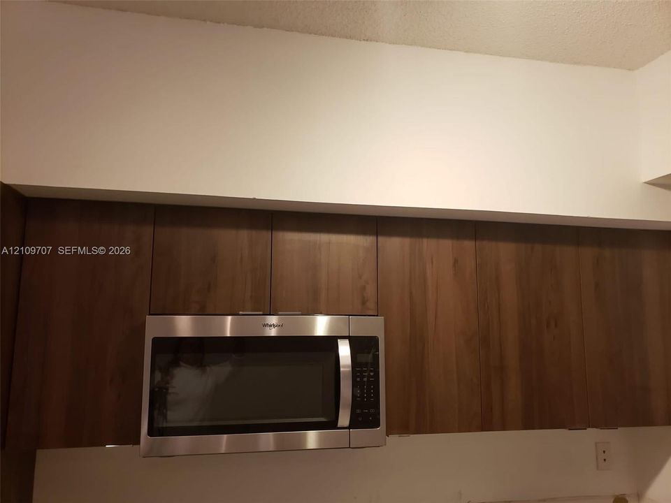 Wood-finish upper cabinetry paired with a stainless steel built-in microwave