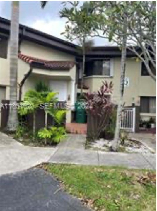 Multi-level exterior featuring stucco siding, decorative tile roofing accents, concrete walkways, and mature landscaping