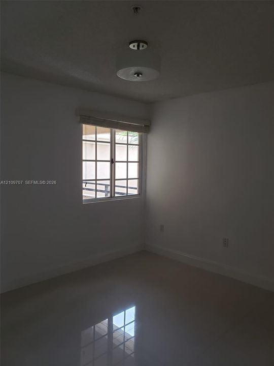 Room featuring neutral wall finishes, glossy tile flooring, a multi-pane window, and a drum-style ceiling light fixture