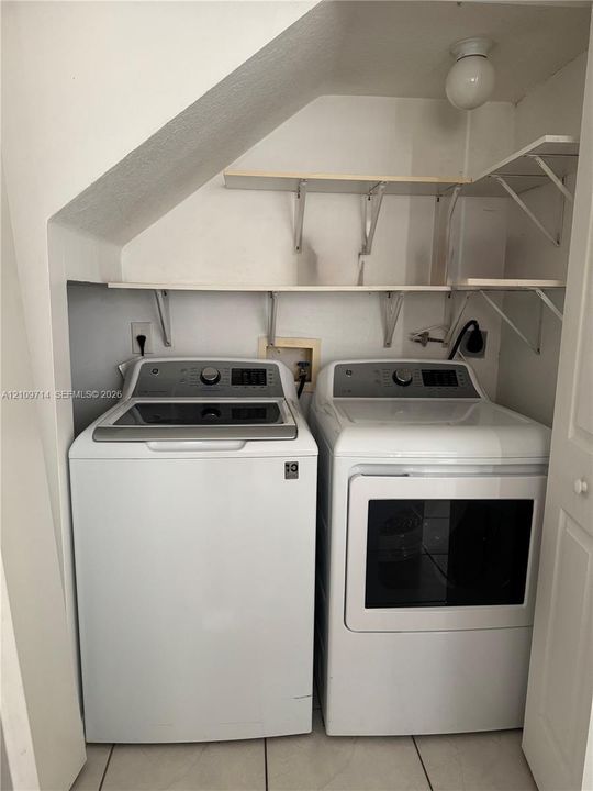 Laundry area featuring built-in shelving, tile flooring, and overhead lighting