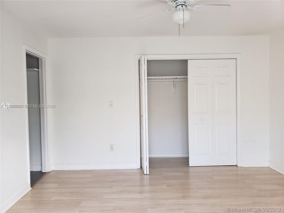 Neutral-toned wood-finish flooring, ceiling fan with integrated lighting, and closet with white double-panel doors