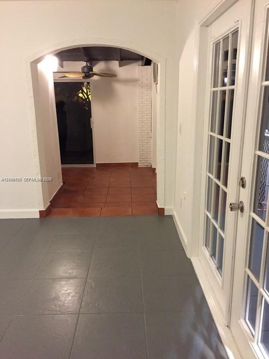 Arched entryway featuring ceramic tile flooring, white brick accent detailing, and glass-paneled double doors