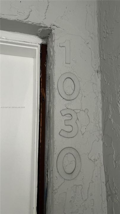 Textured stucco exterior wall featuring raised numerical address signage