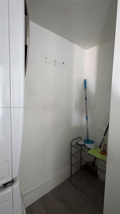 Enclosed utility alcove featuring wood-finish flooring and white walls