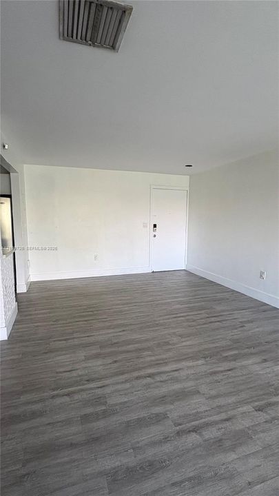 Neutral-toned interior space featuring wood-finish flooring and a white entry door