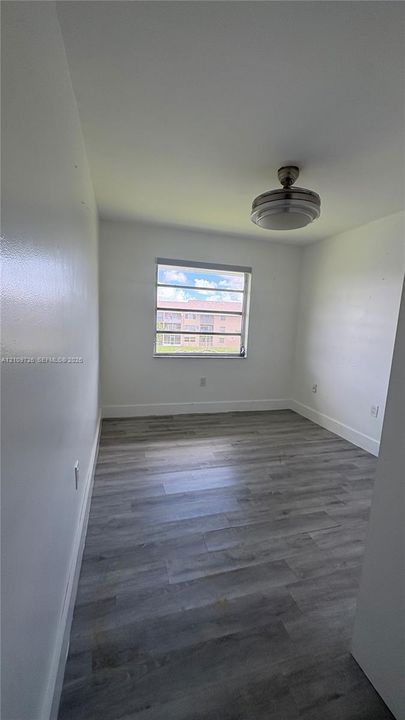 Neutral-toned room featuring wood-finish flooring, a single-pane horizontal window, and a ceiling-mounted light fixture