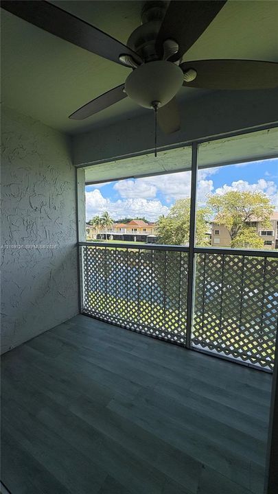 Screened balcony featuring wood-finish flooring, a ceiling fan with integrated lighting, and white lattice railing