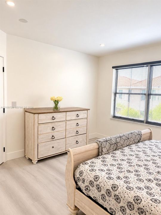 Neutral-toned interior featuring wood-finish flooring, recessed lighting, and a large window with dark-toned frames