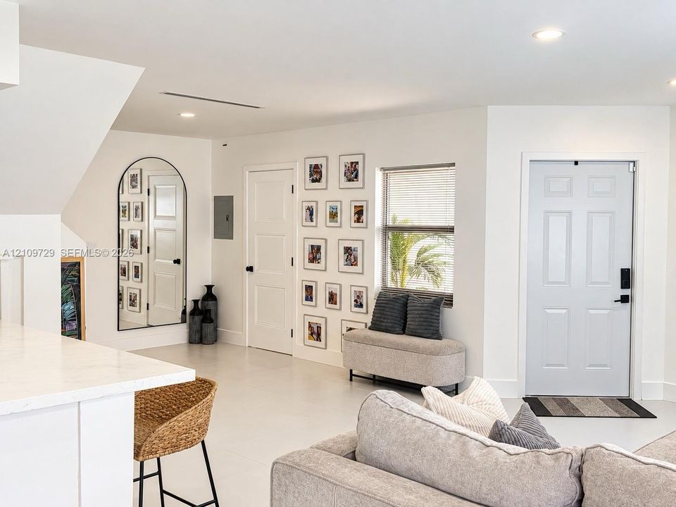 Interior space featuring neutral tile flooring, recessed ceiling lighting, a six-panel entry door with smart lock technology, and an arched-frame mirror