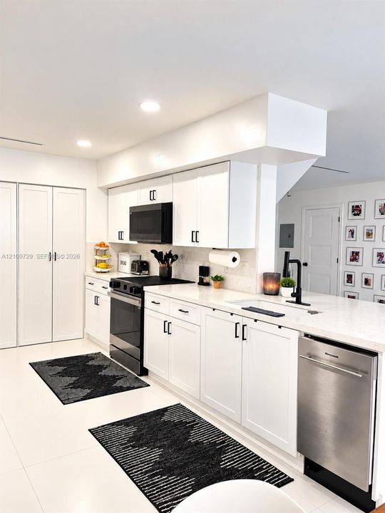 Kitchen featuring white cabinetry with matte black hardware, stone-finish countertops, recessed lighting, and a stainless steel dishwasher