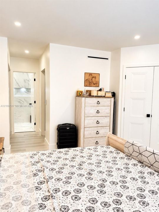 Recessed ceiling lighting, wood-finish flooring, and white paneled doors with matte black hardware