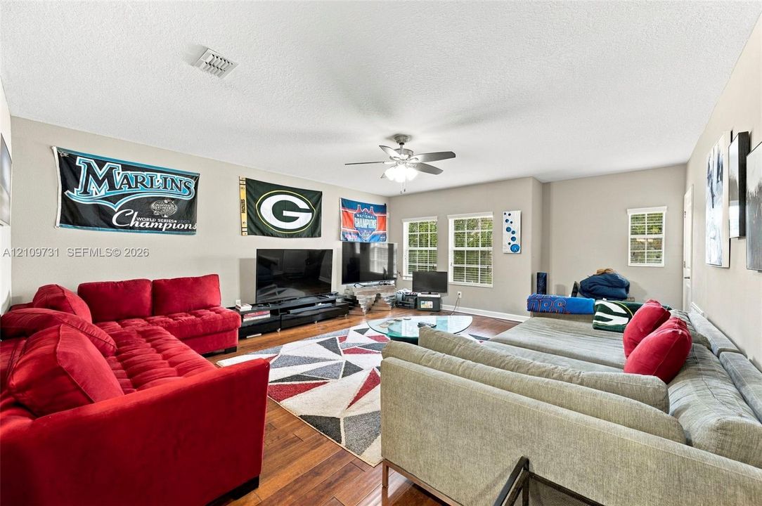 Spacious interior featuring wood-finish flooring, multi-pane windows, and a central ceiling fan with integrated lighting