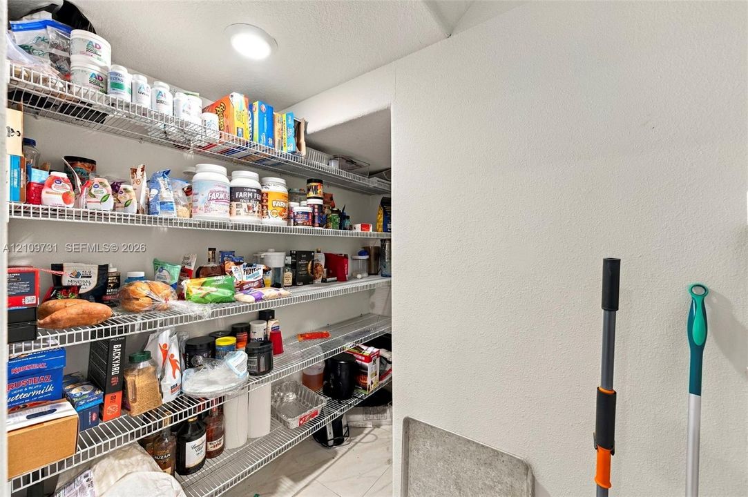 Walk-in pantry featuring multiple tiers of white wire shelving and recessed ceiling lighting