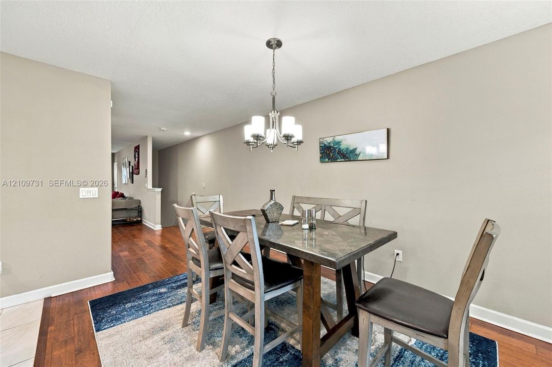 Wood-finish flooring and a central chandelier with white glass shades