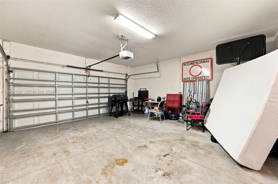 Multi-car garage featuring a sectional metal overhead door, concrete flooring, and linear fluorescent overhead lighting
