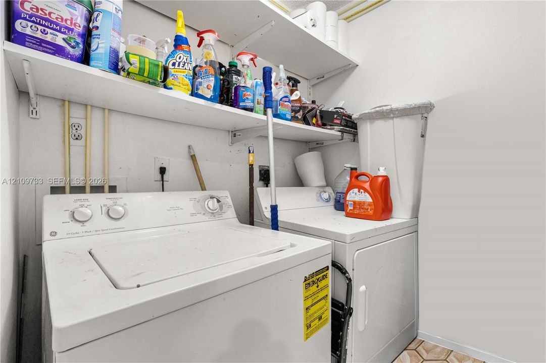 Laundry space featuring built-in white shelving and tile flooring